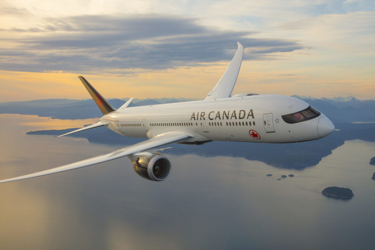 A large air Canada passenger jet flying through a cloudy sky