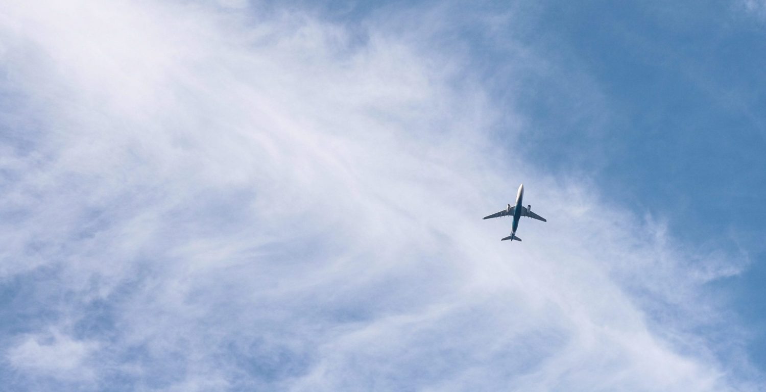 A large airplane flying high up in the air on a cloudy day