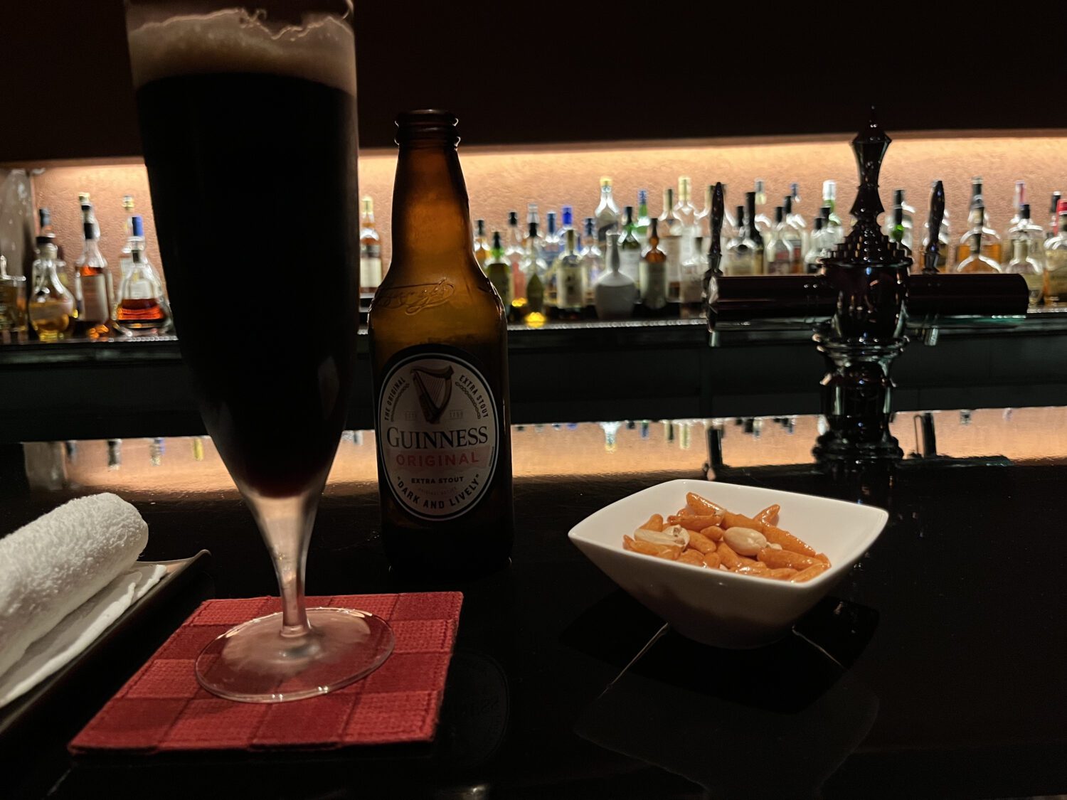 A glass of beer and a bowl of chips on a bar counter